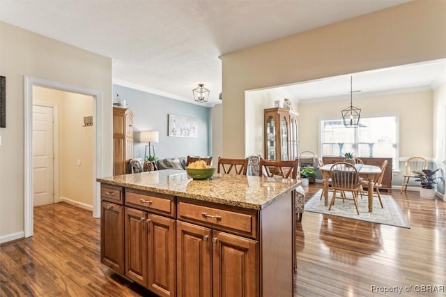 kitchen with pendant lighting, a center island, dark wood-type flooring, a kitchen breakfast bar, and light stone counters