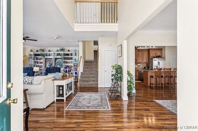 entrance foyer with ceiling fan, crown molding, a towering ceiling, and dark hardwood / wood-style floors