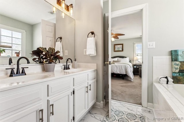 bathroom featuring tiled tub, ceiling fan, and vanity