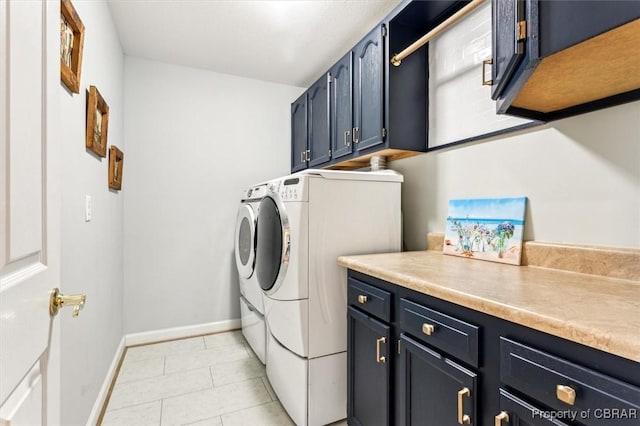 clothes washing area with cabinets, light tile patterned floors, and washing machine and clothes dryer