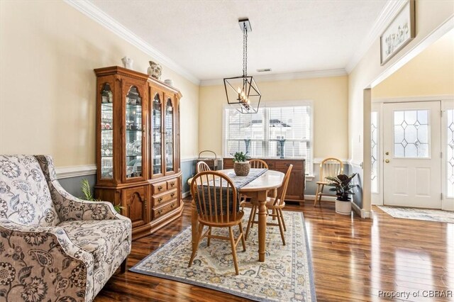 dining space featuring dark wood-type flooring, a chandelier, and ornamental molding