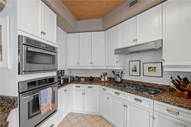 kitchen with light tile patterned flooring, dark stone countertops, white cabinetry, and stainless steel appliances