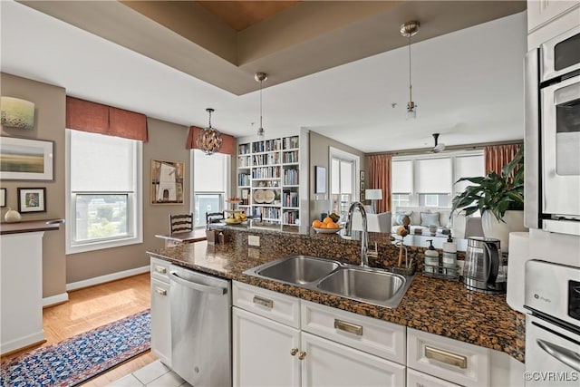 kitchen featuring appliances with stainless steel finishes, dark stone counters, sink, pendant lighting, and white cabinetry