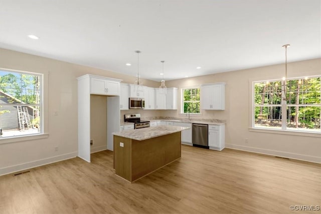 73 Jamestown Ln, Bracey, VA 23919 - kitchen with appliances with stainless steel finishes, white cabinets, light wood finished floors, a center island, and decorative light fixtures