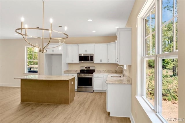 73 Jamestown Ln, Bracey, VA 23919 - kitchen featuring stainless steel appliances, a kitchen island, light wood-type flooring, a chandelier, and white cabinetry