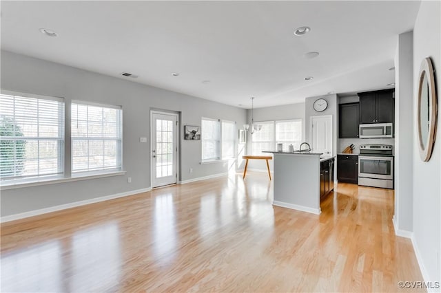 living room featuring a chandelier, light wood-type flooring, a wealth of natural light, and sink