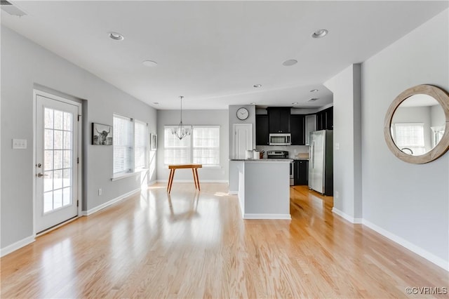 kitchen with an inviting chandelier, a kitchen island, stainless steel appliances, and light hardwood / wood-style flooring