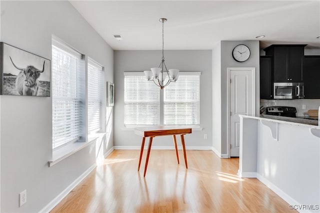 kitchen with a notable chandelier, plenty of natural light, hanging light fixtures, and light hardwood / wood-style flooring