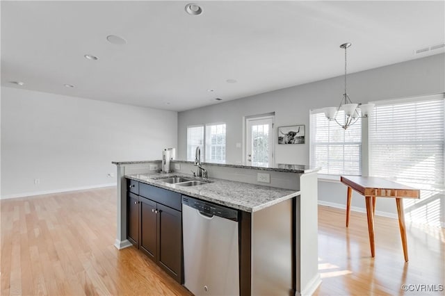 kitchen with sink, light stone counters, stainless steel dishwasher, pendant lighting, and a kitchen island with sink