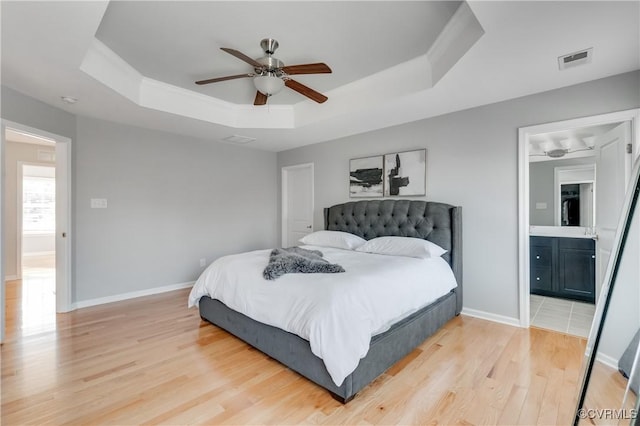 bedroom featuring ensuite bathroom, a raised ceiling, crown molding, ceiling fan, and light hardwood / wood-style floors