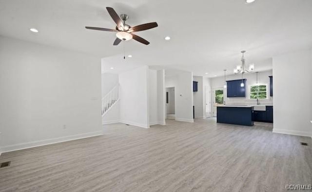 unfurnished living room featuring ceiling fan with notable chandelier, light hardwood / wood-style floors, and sink