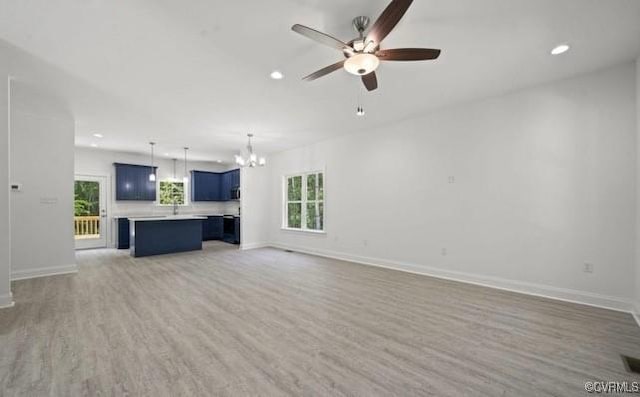 unfurnished living room with light hardwood / wood-style floors and ceiling fan with notable chandelier