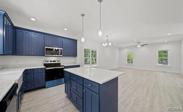 kitchen with blue cabinets, a kitchen island, ceiling fan with notable chandelier, and appliances with stainless steel finishes