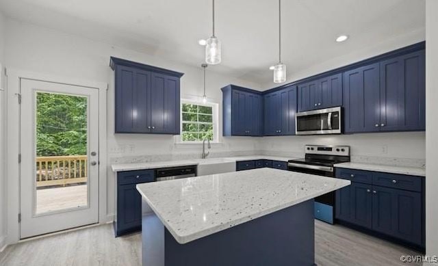 kitchen featuring light stone counters, a kitchen island, hanging light fixtures, and appliances with stainless steel finishes