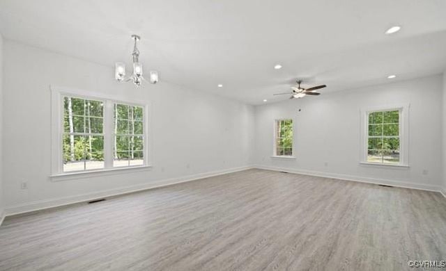 spare room featuring ceiling fan with notable chandelier and light hardwood / wood-style flooring