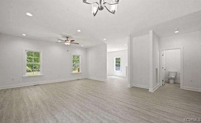 unfurnished living room with ceiling fan with notable chandelier and light wood-type flooring