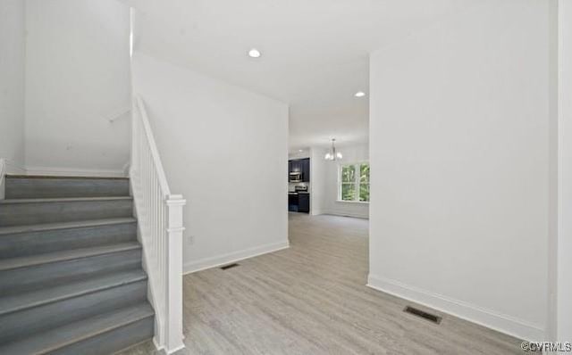 staircase featuring hardwood / wood-style floors and a chandelier