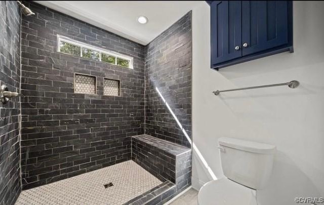 bathroom with a tile shower, toilet, and tile patterned floors