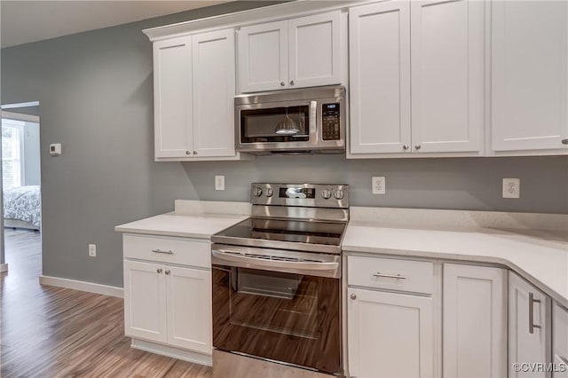 kitchen with light wood-type flooring, white cabinetry, and appliances with stainless steel finishes