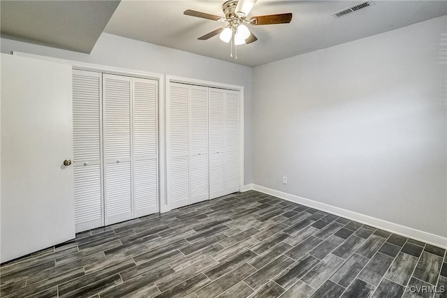 unfurnished bedroom featuring two closets and ceiling fan