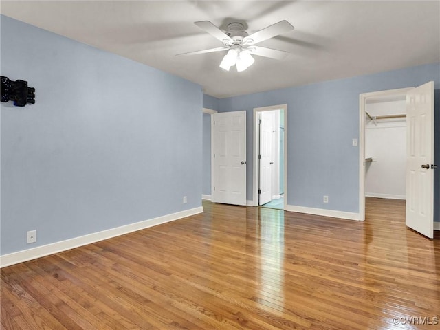 unfurnished bedroom with ceiling fan, light hardwood / wood-style floors, a walk in closet, and a closet