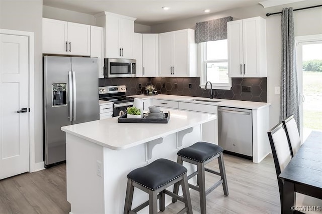 kitchen featuring a center island, sink, appliances with stainless steel finishes, a kitchen bar, and white cabinetry