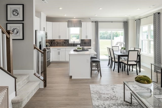 kitchen featuring white cabinetry, sink, a kitchen breakfast bar, backsplash, and a kitchen island