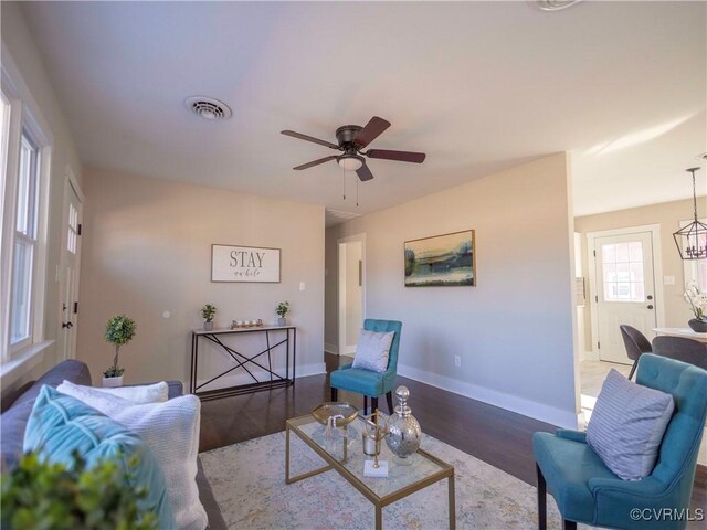 living room featuring ceiling fan with notable chandelier and hardwood / wood-style floors