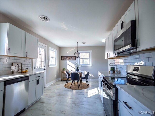 kitchen with backsplash, white cabinetry, and stainless steel appliances