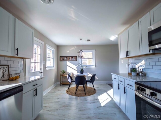 kitchen featuring white cabinets, backsplash, appliances with stainless steel finishes, and pendant lighting