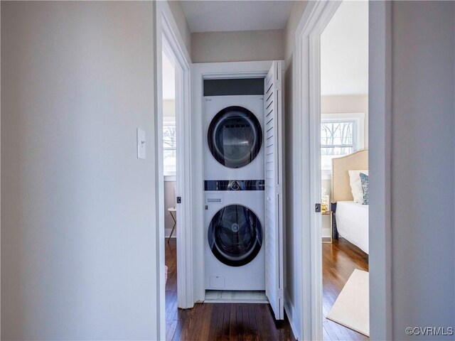 laundry room featuring stacked washer / drying machine and dark hardwood / wood-style floors