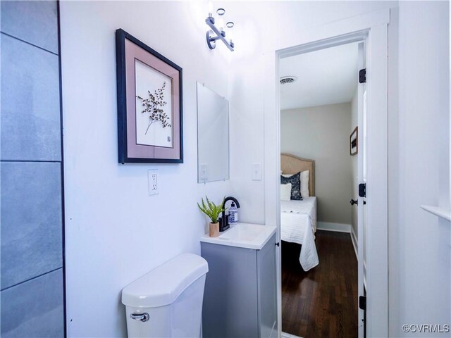 bathroom with hardwood / wood-style flooring, toilet, and vanity