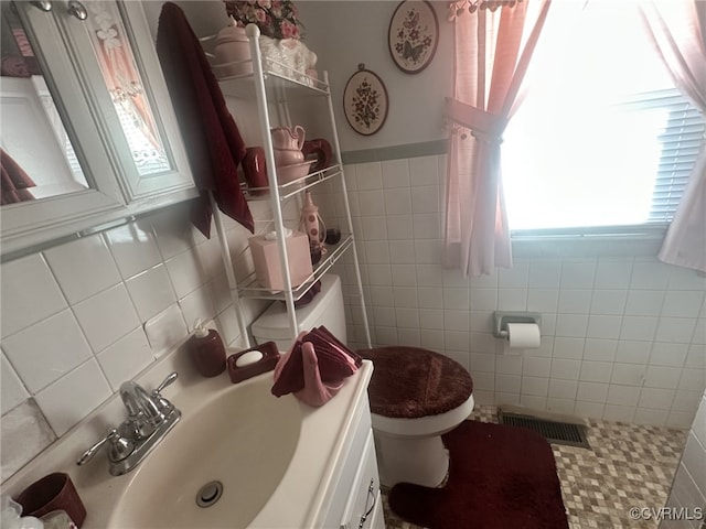 bathroom featuring vanity, toilet, and tile walls