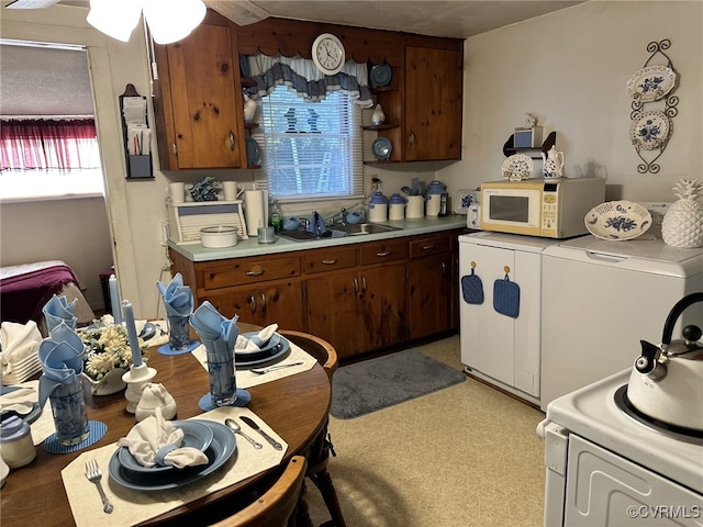 kitchen with range, a wealth of natural light, washer / dryer, and sink