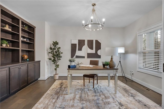 home office with dark hardwood / wood-style flooring and an inviting chandelier