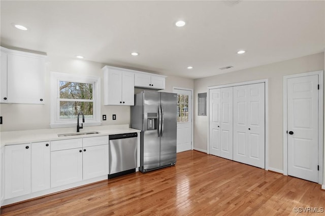 kitchen with white cabinets, stainless steel appliances, light hardwood / wood-style flooring, and sink