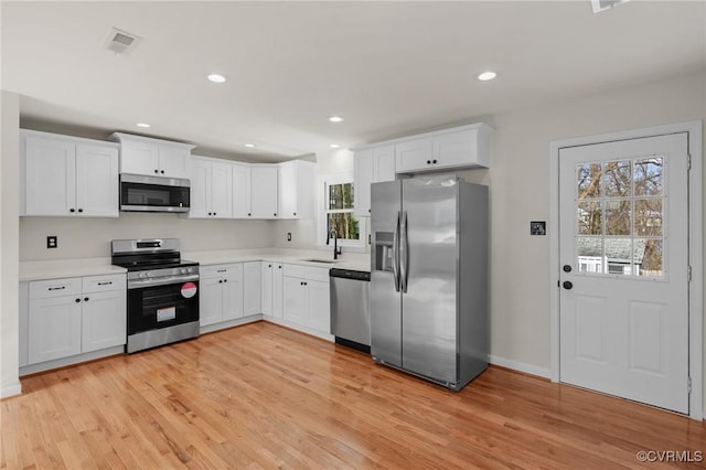 kitchen featuring white cabinets, light hardwood / wood-style floors, sink, and stainless steel appliances