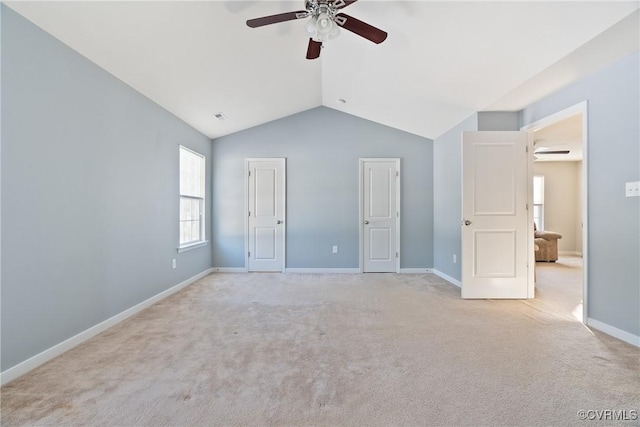 unfurnished bedroom with light carpet, lofted ceiling, a ceiling fan, and baseboards