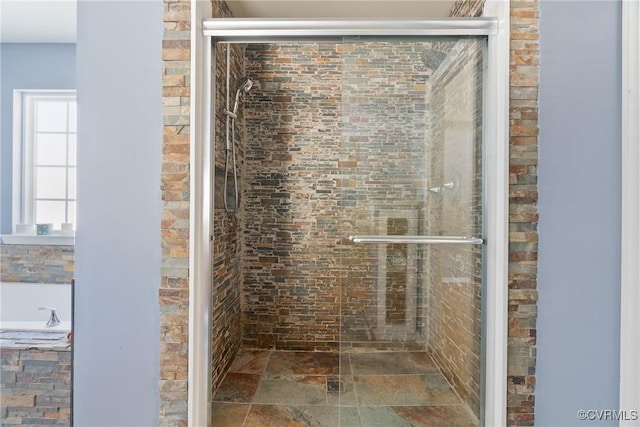 bathroom featuring stone tile flooring and a shower stall