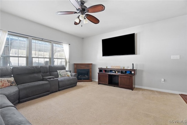 living room with light carpet, ceiling fan, a fireplace, and baseboards