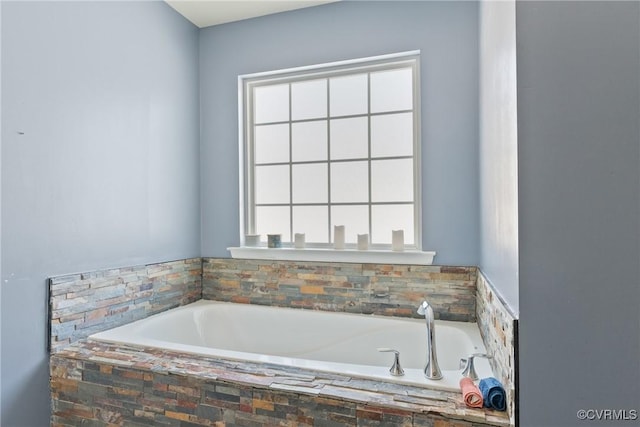 bathroom featuring a relaxing tiled tub and a wealth of natural light