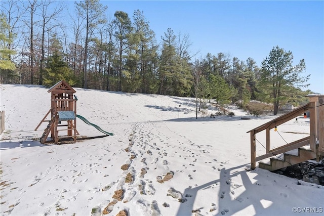 snowy yard featuring a playground