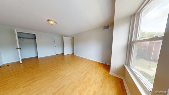 unfurnished bedroom with light hardwood / wood-style floors and multiple windows