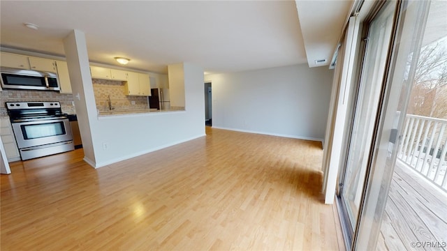 kitchen featuring sink, appliances with stainless steel finishes, light wood-type flooring, and backsplash