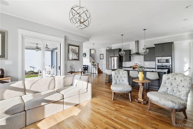 living room with light hardwood / wood-style floors, crown molding, and a notable chandelier