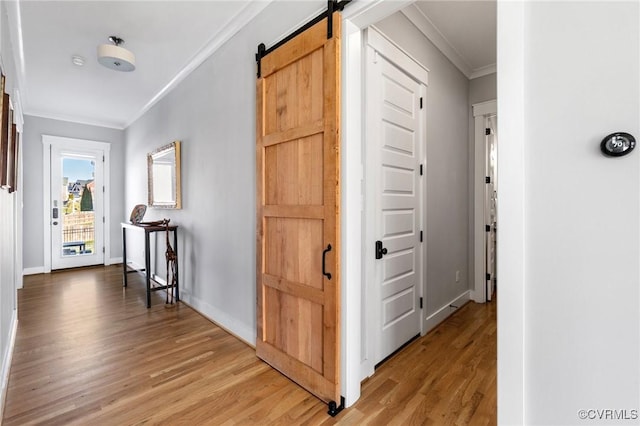 hall featuring wood-type flooring, ornamental molding, and a barn door