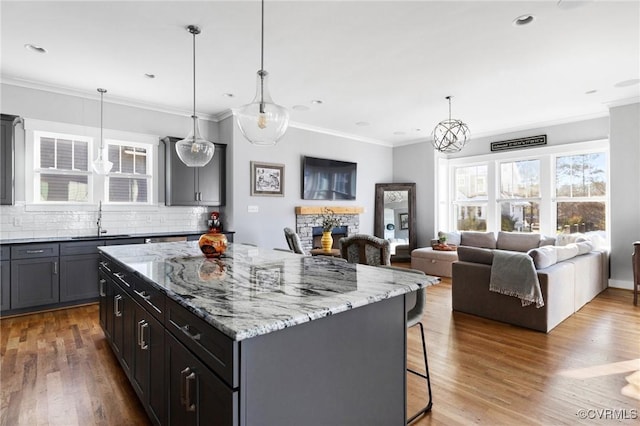 kitchen with hardwood / wood-style flooring, backsplash, a kitchen breakfast bar, a kitchen island, and pendant lighting