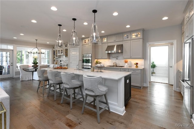 11163 Independence Rd, Ashland, VA 23005 - kitchen with pendant lighting, dark wood-type flooring, a large island with sink, wall chimney range hood, and stainless steel appliances