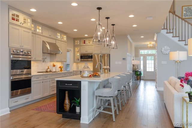 11163 Independence Rd, Ashland, VA 23005 - kitchen featuring a center island with sink, wall chimney exhaust hood, decorative backsplash, white cabinetry, and stainless steel appliances