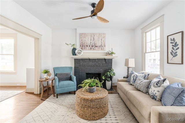 living room featuring ceiling fan, a fireplace, and light hardwood / wood-style flooring